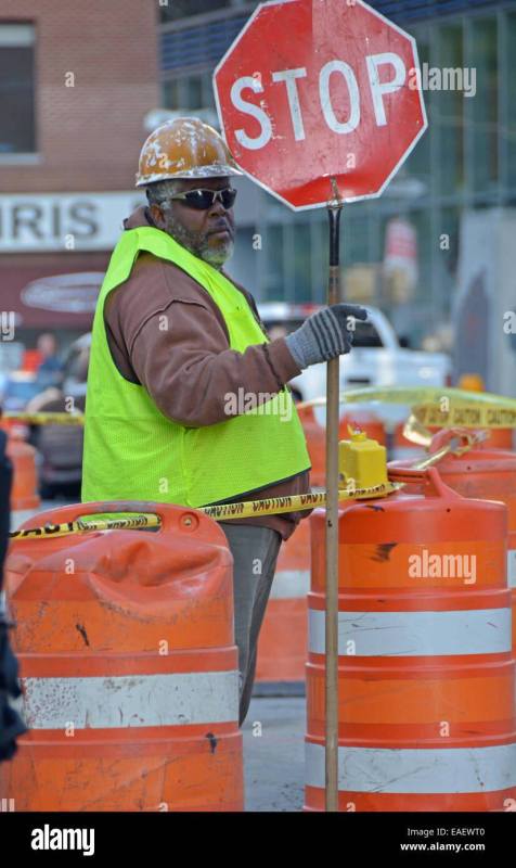 construction-worker-holding-a-stop-sign-to-direct-auto-pedestrian-EAEWT0.jpg